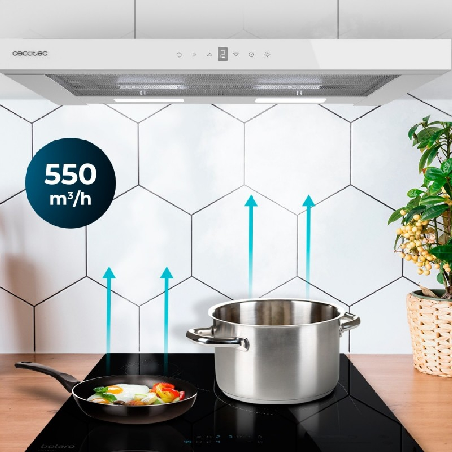 Olla de acero inoxidable y sartén con huevo frito en placa de inducción bajo campana extractora blanca.
