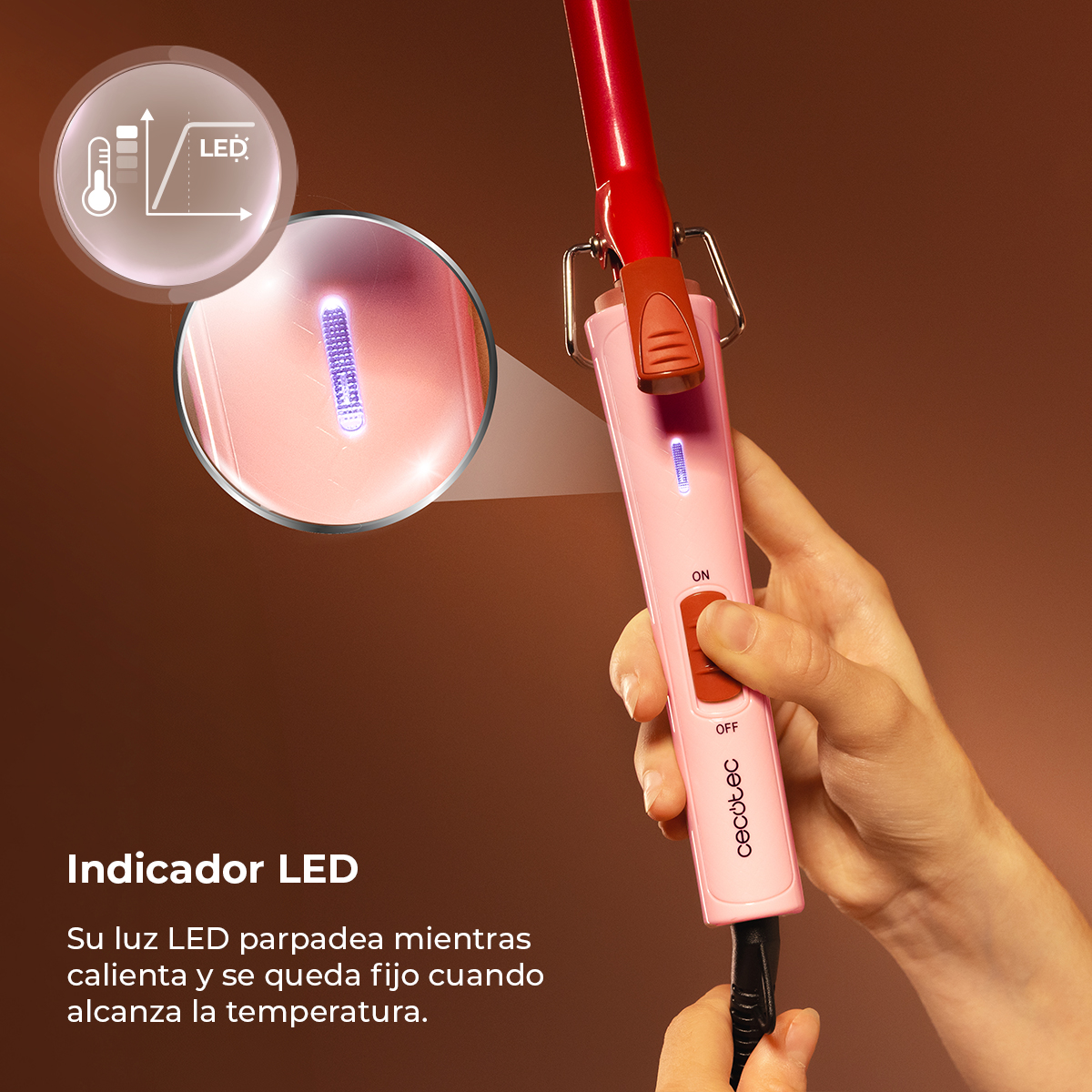 Una mano tiene un ferro arricciacapelli rosa e rosso con un indicatore LED acceso.