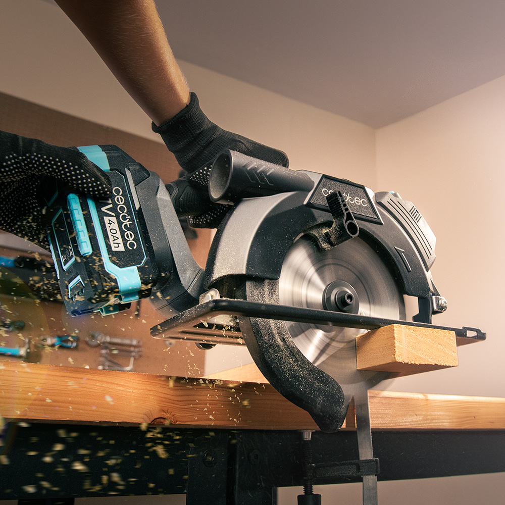 Una persona usa una sierra circular portátil para cortar madera en un taller.