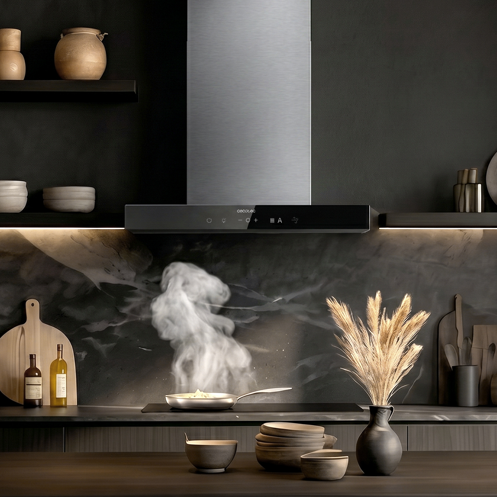 Campana extractora moderna sobre una placa de cocina en una cocina oscura con sartén humeante.