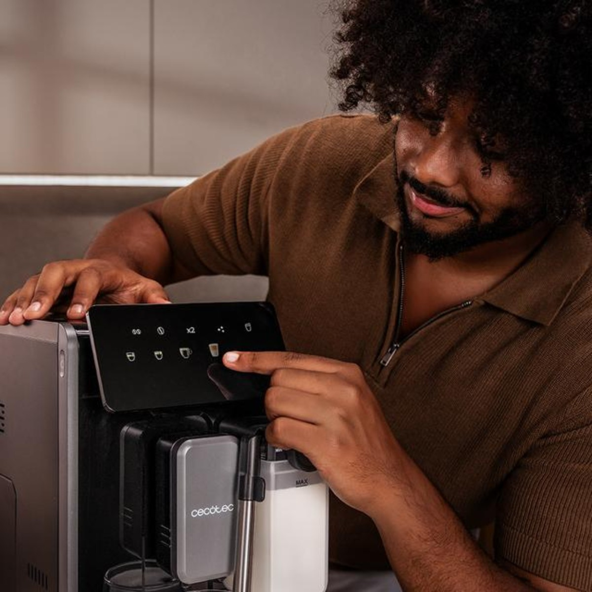 Ein Mann mit lockigem Haar bedient die Touch-Bedienfläche einer modernen Kaffeemaschine.
