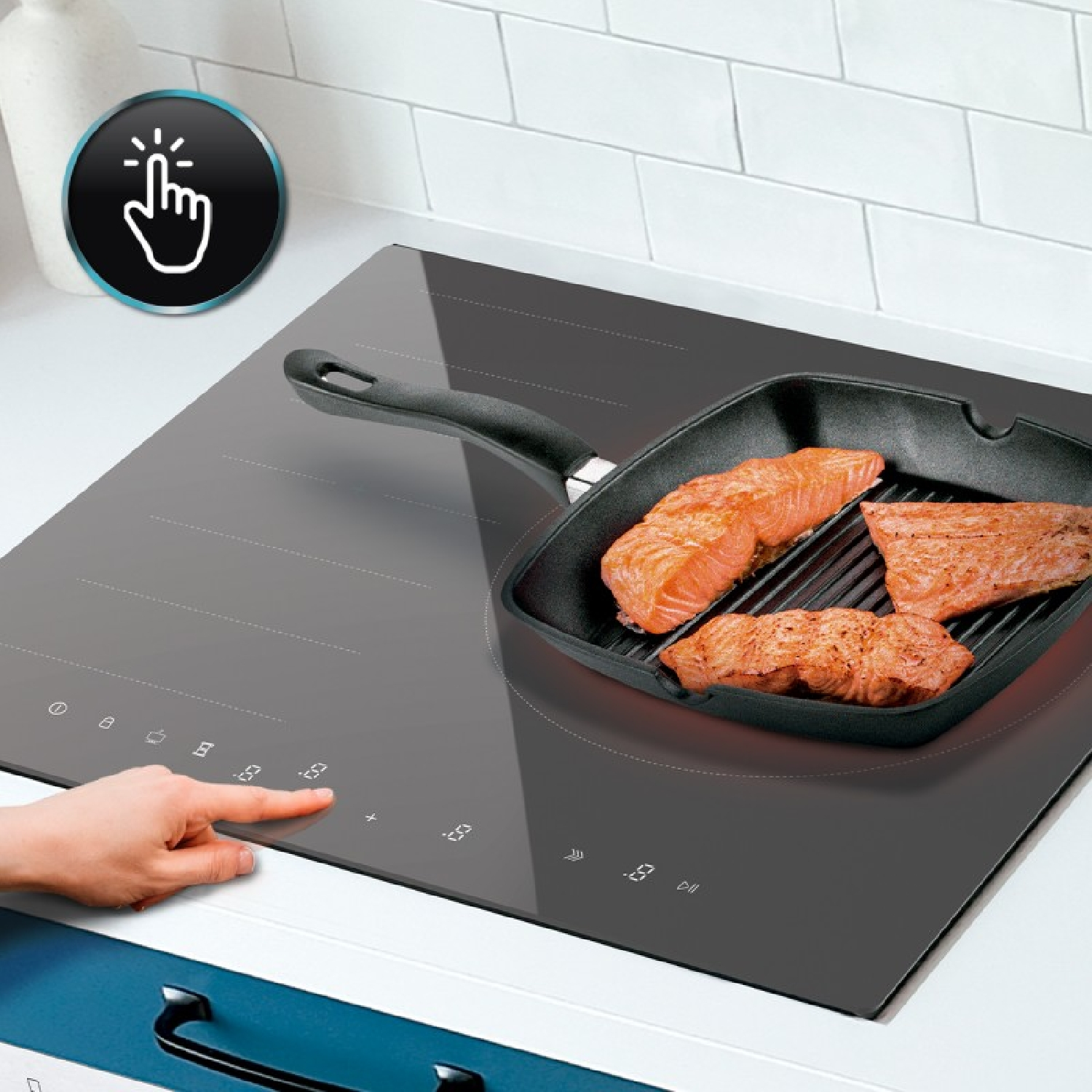 Una mano toca el panel táctil de una placa de inducción gris con salmón en una sartén.