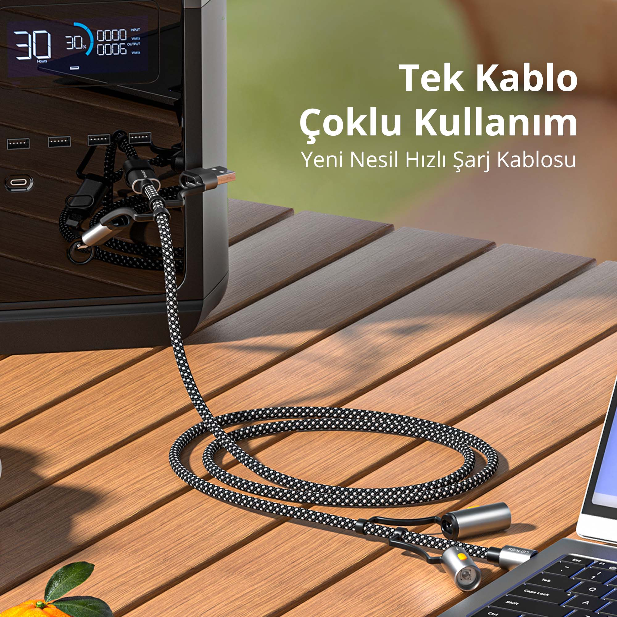 Örgülü bir USB şarj kablosu ahşap masa üzerinde taşınabilir güç istasyonu ve dizüstü bilgisayara bağlı.