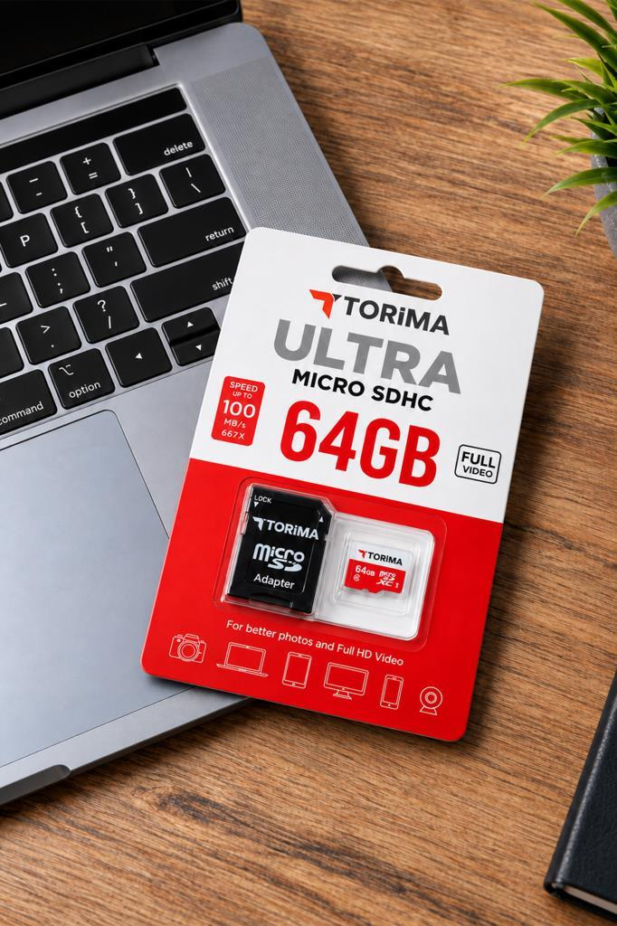 Ambalajında bir Torima 64GB Micro SDHC kart, dizüstü bilgisayarın yanında ahşap masada duruyor.