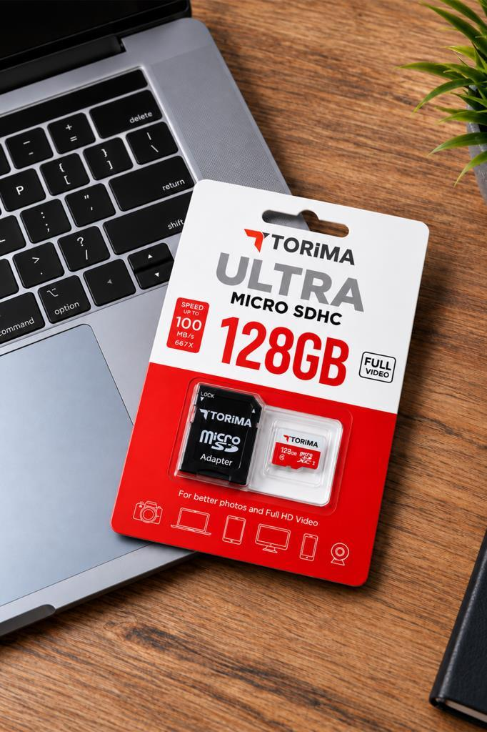 Ahşap bir masa üzerinde dizüstü bilgisayarın yanında Torima 128GB Micro SDXC hafıza kartı.