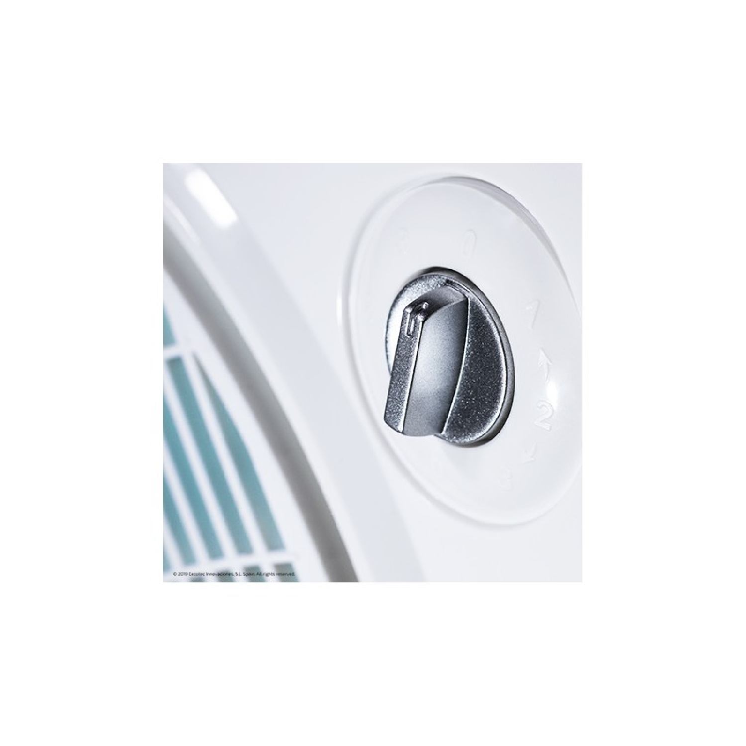 Primer plano de un mando giratorio plateado en un electrodoméstico blanco, con números y flechas.