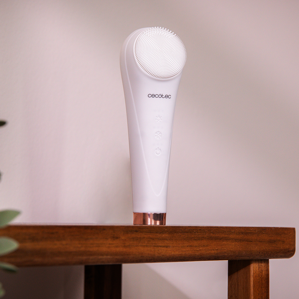 Un cepillo limpiador facial blanco de Cecotec sobre un mueble de madera.