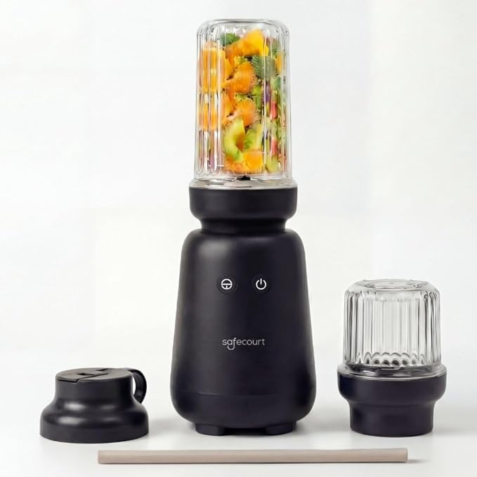 A black blender with a filled glass cup, extra cup, lid, and straw on a white background.