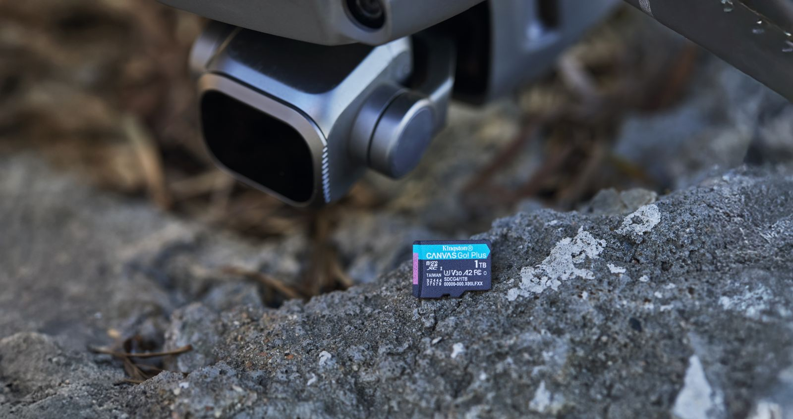 Une carte microSD Kingston de 1 To repose sur un rocher gris sous la caméra d'un drone.