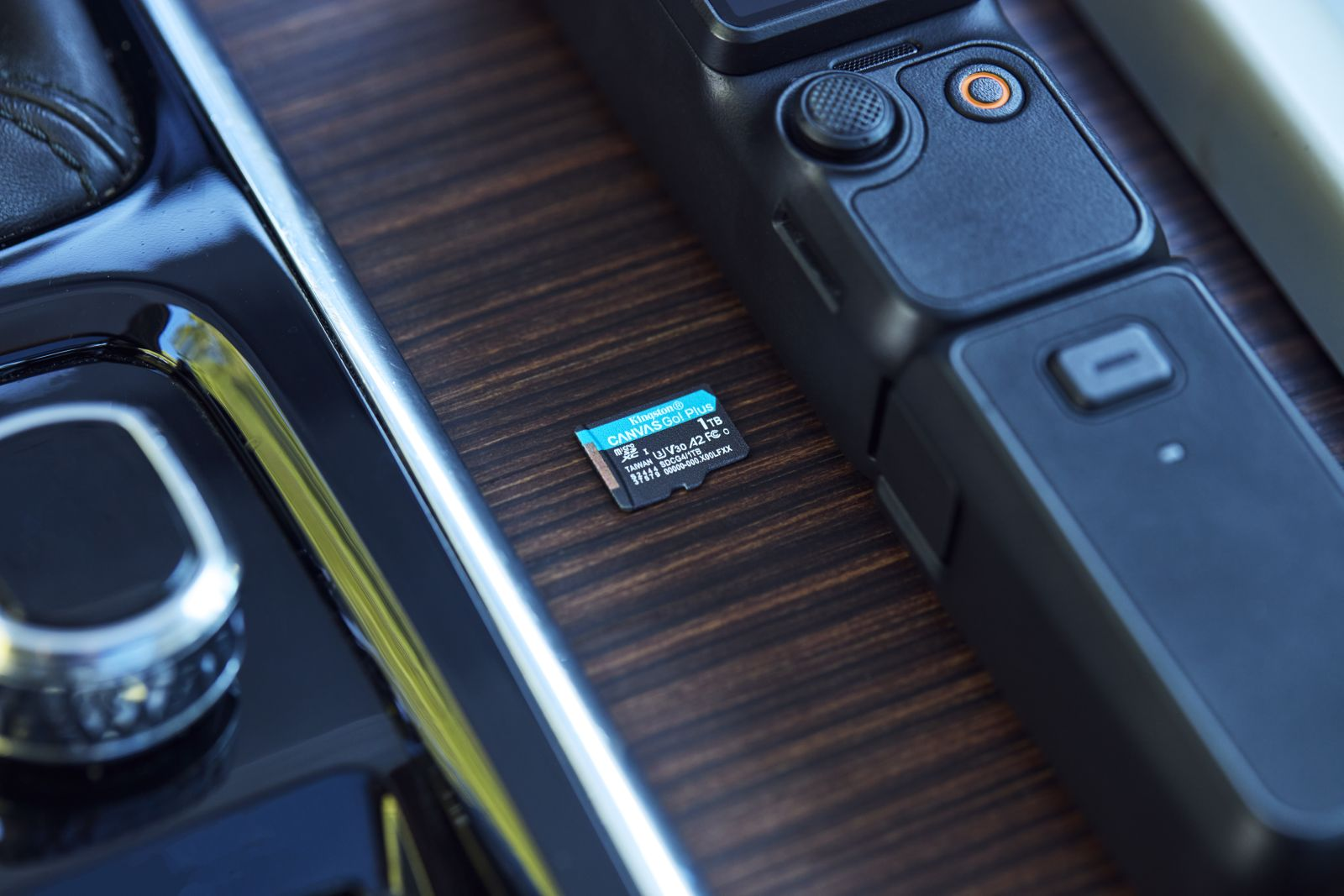 Une carte microSD Kingston et une caméra vidéo noire reposent sur une surface en bois dans une voiture.