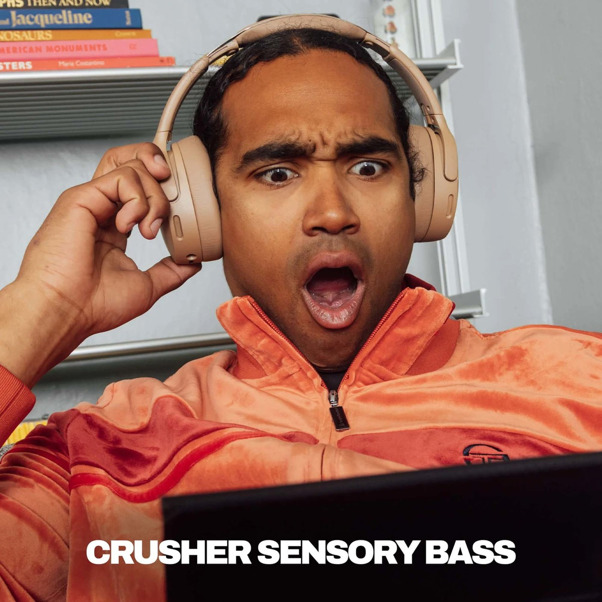 Hombre con auriculares y chaqueta naranja muestra una expresión de asombro.