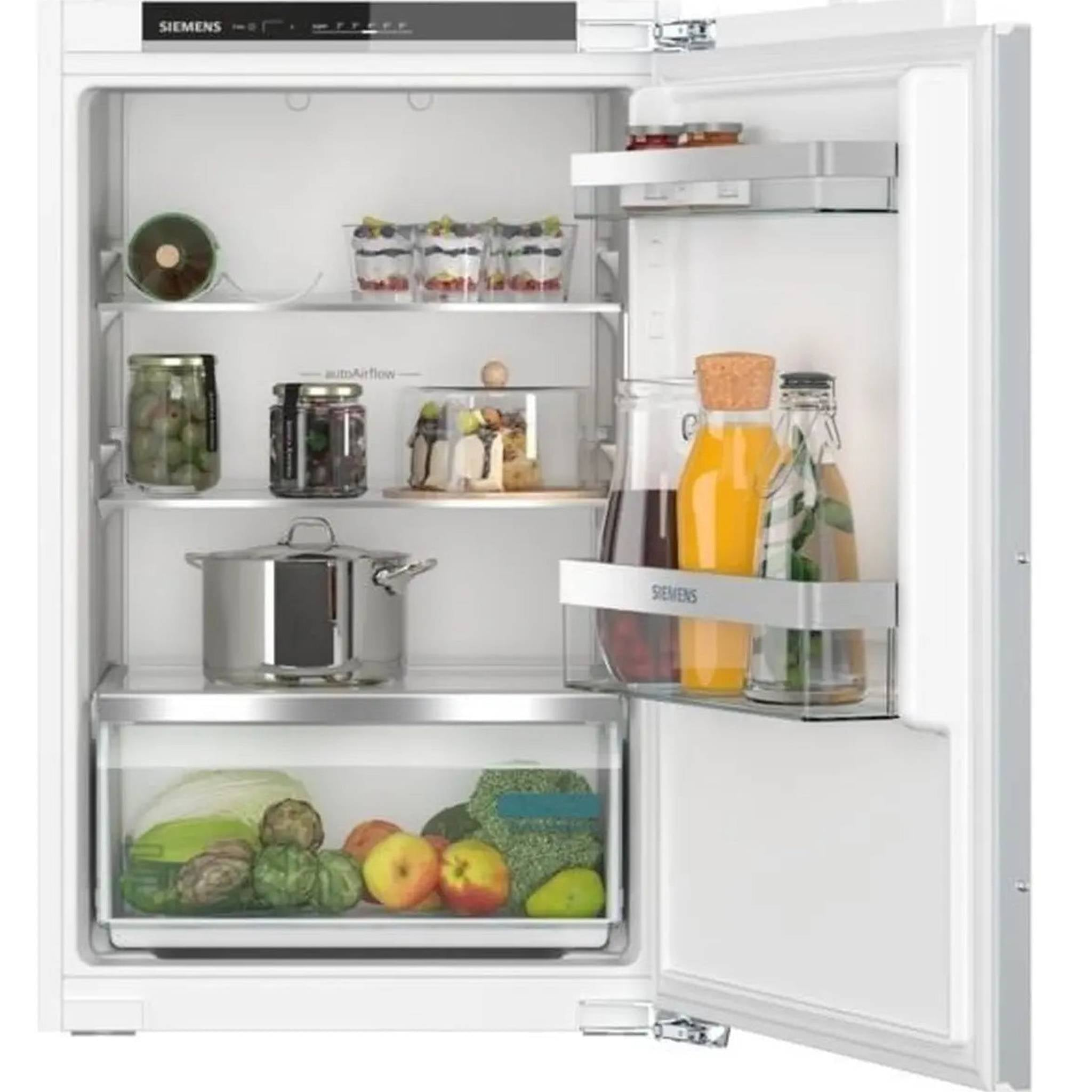 Een witte Siemens inbouwkoelkast met open deur, gevuld met eten, potten en verse groenten.