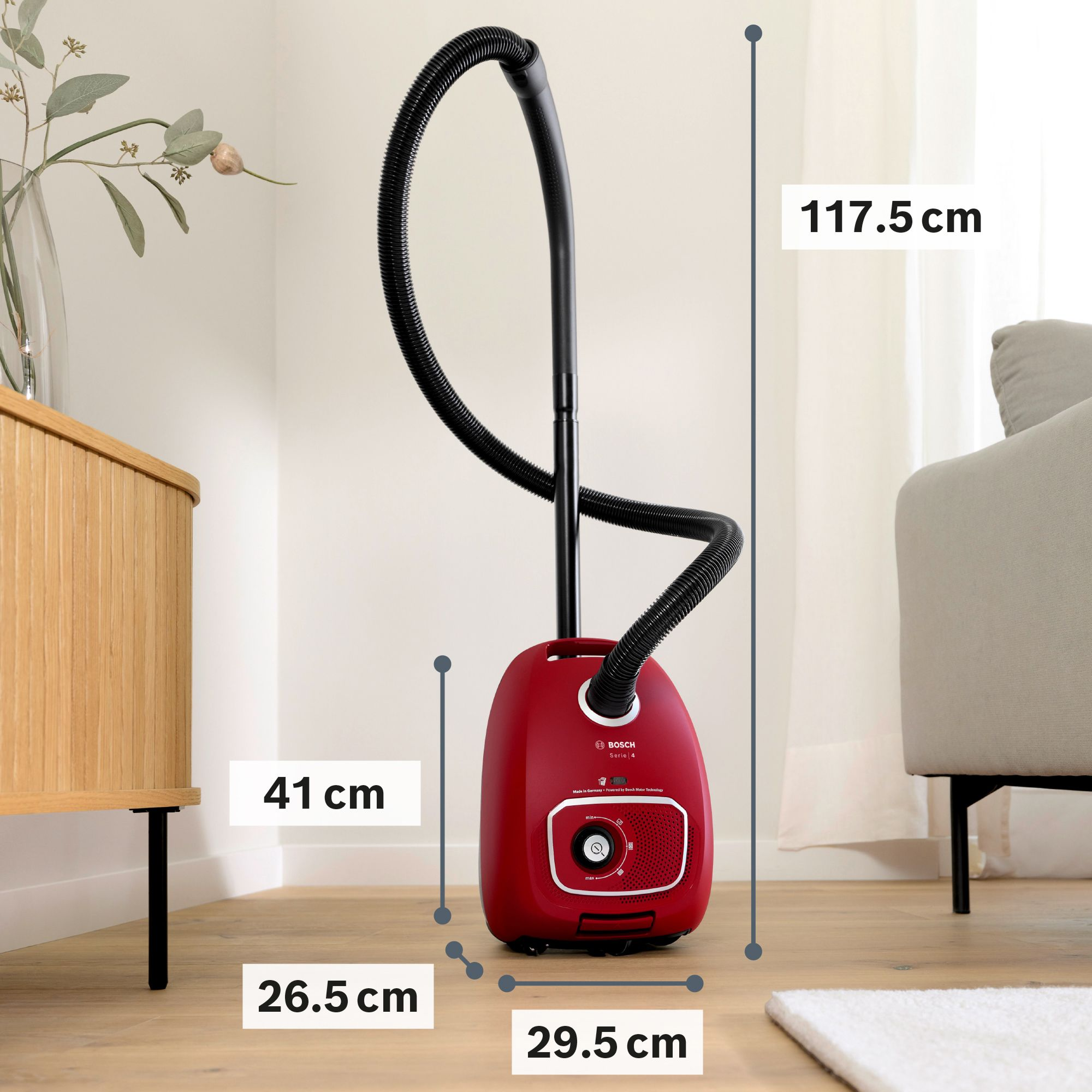A red Bosch vacuum cleaner with dimensions shown on a wooden floor in a room.