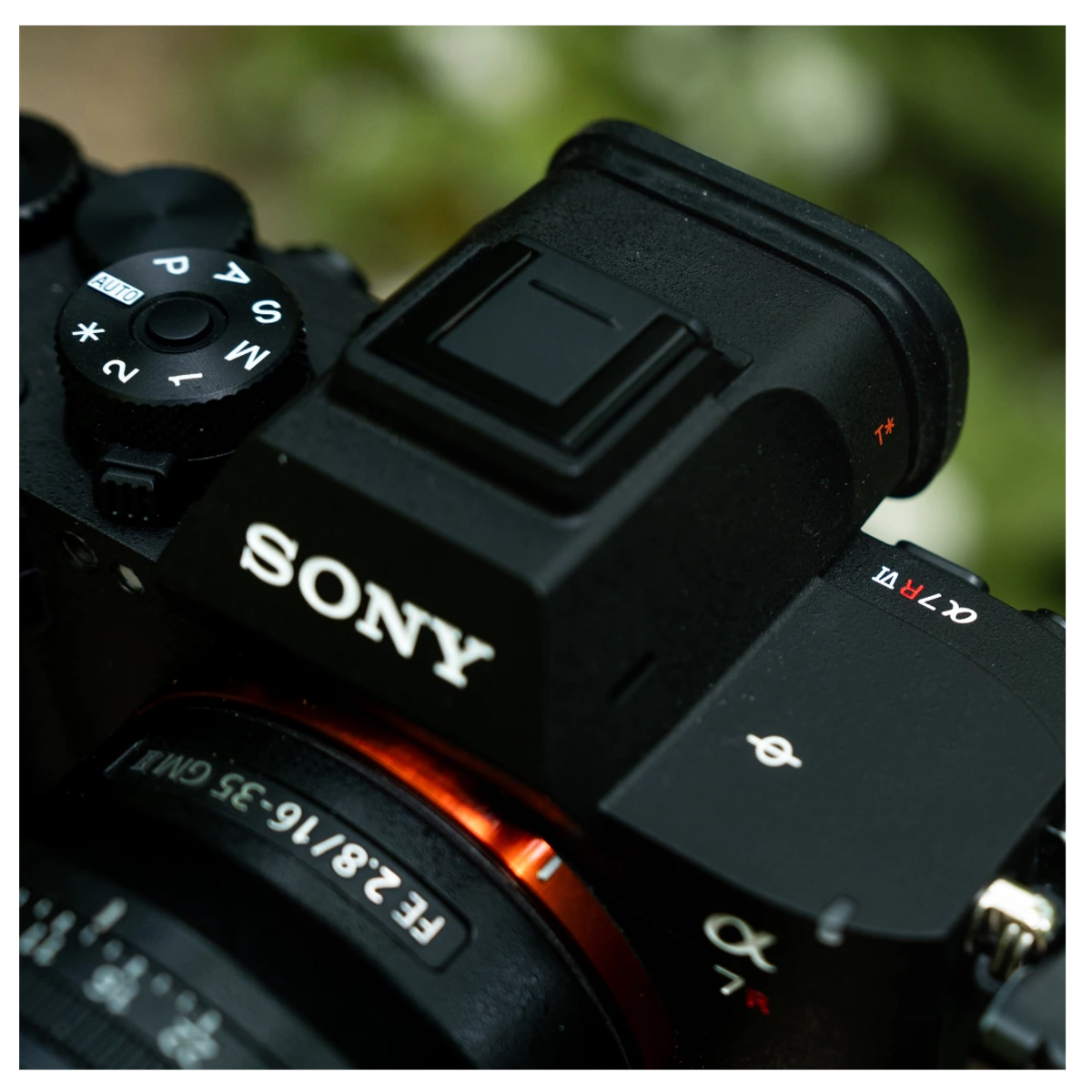 Bulanık arka plan önünde, FE 2.8/16-35 mm lens takılı siyah bir Sony Alpha kameranın yakın çekimi.