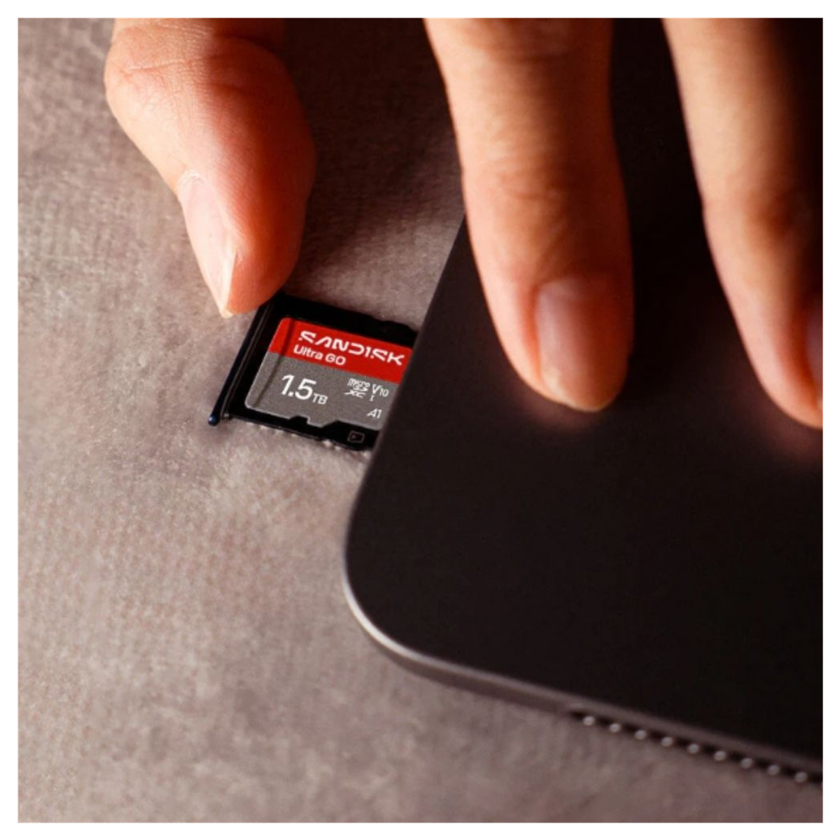Une main insère une carte micro SD SanDisk Ultra GO de 1,5 To dans une tablette.