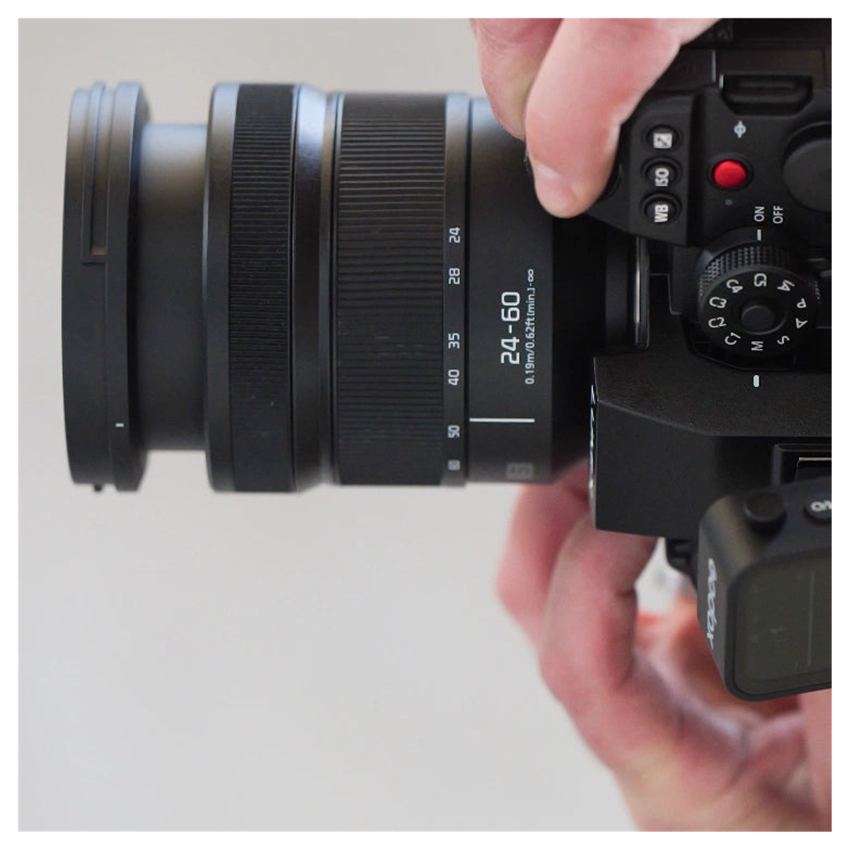 Nahaufnahme einer Person, die eine professionelle schwarze Kamera mit 24-60mm Objektiv hält.