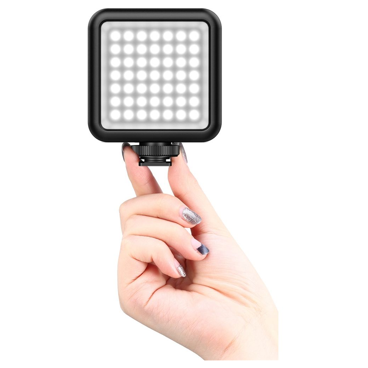 A hand holding a small, square LED video light with rounded corners against a white background.