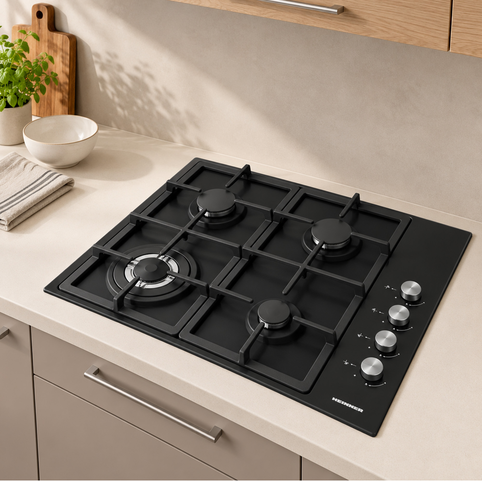 A black four-burner gas cooktop with silver control knobs is set on a beige kitchen counter.