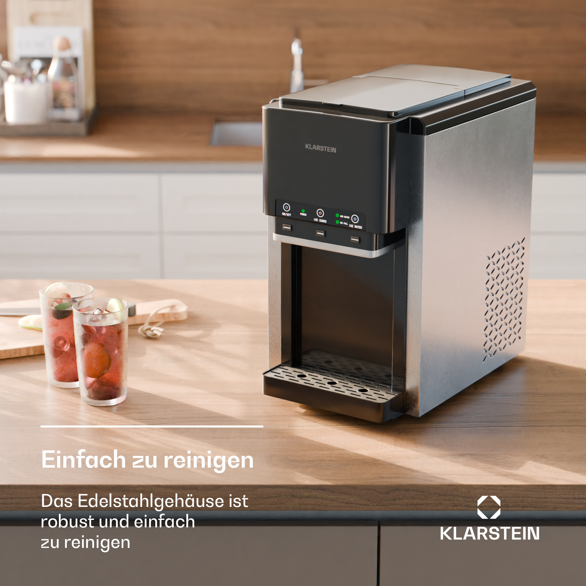 Edelstahl-Eiswürfelbereiter von Klarstein auf einer Holzarbeitsplatte neben zwei Gläsern mit rotem Getränk.