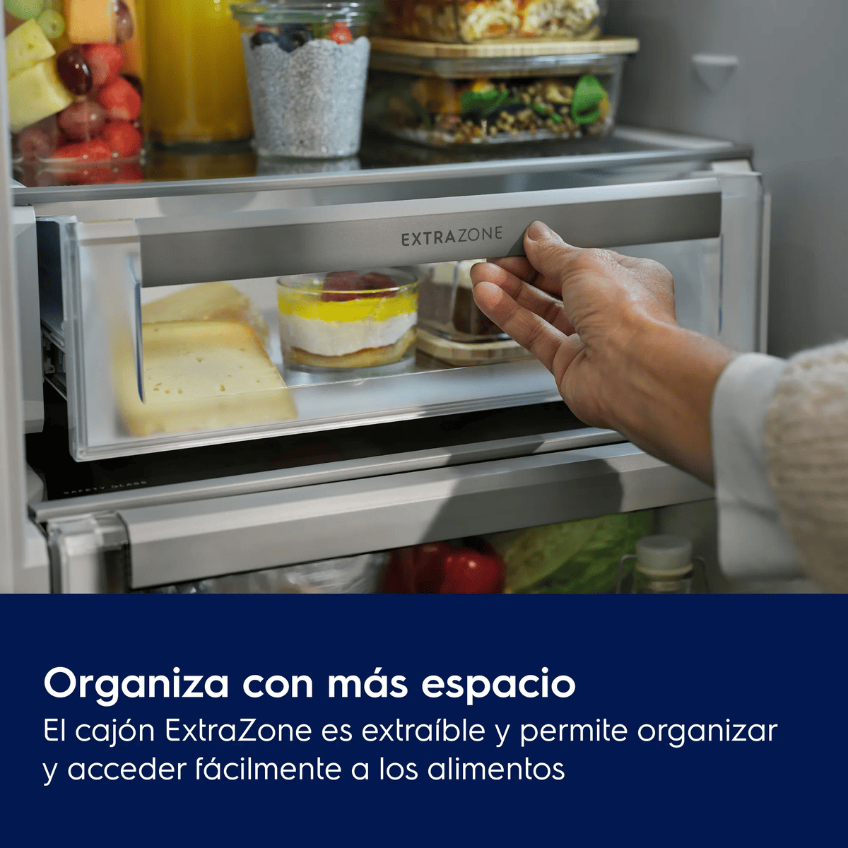 Una mano abre el cajón ExtraZone de un refrigerador con queso y postres, con texto abajo.