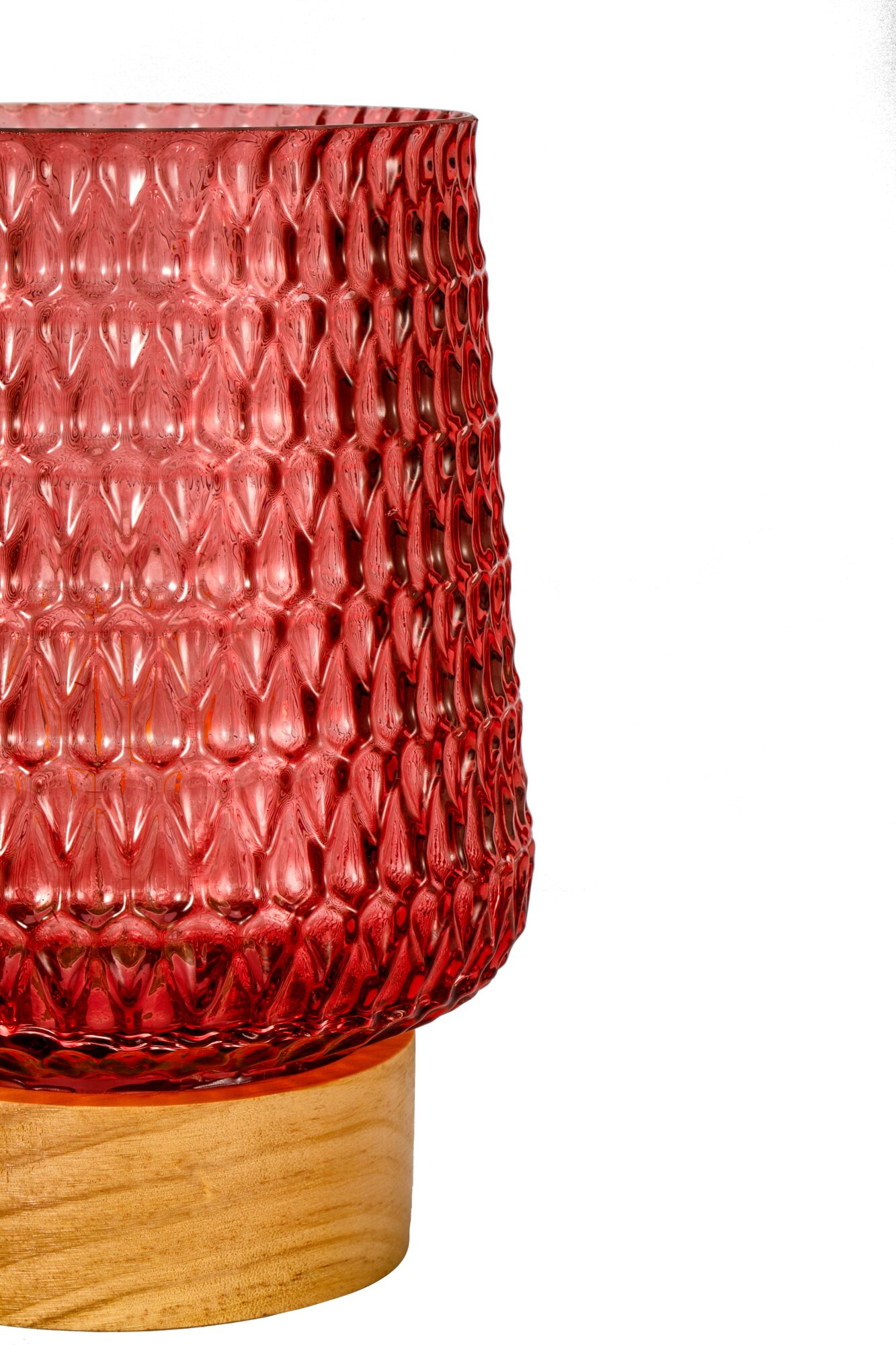 Eine rote Glastischlampe mit Muster steht auf einem runden Holzsockel vor einem weißen Hintergrund.