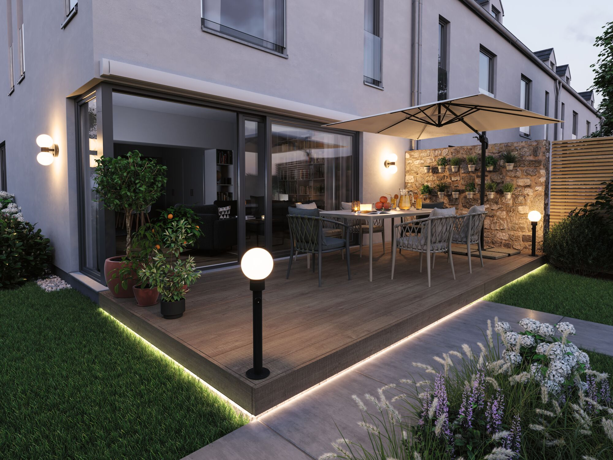 Moderne Terrasse mit Esstisch, großem Sonnenschirm und stimmungsvoller Beleuchtung an einem Wohnhaus.