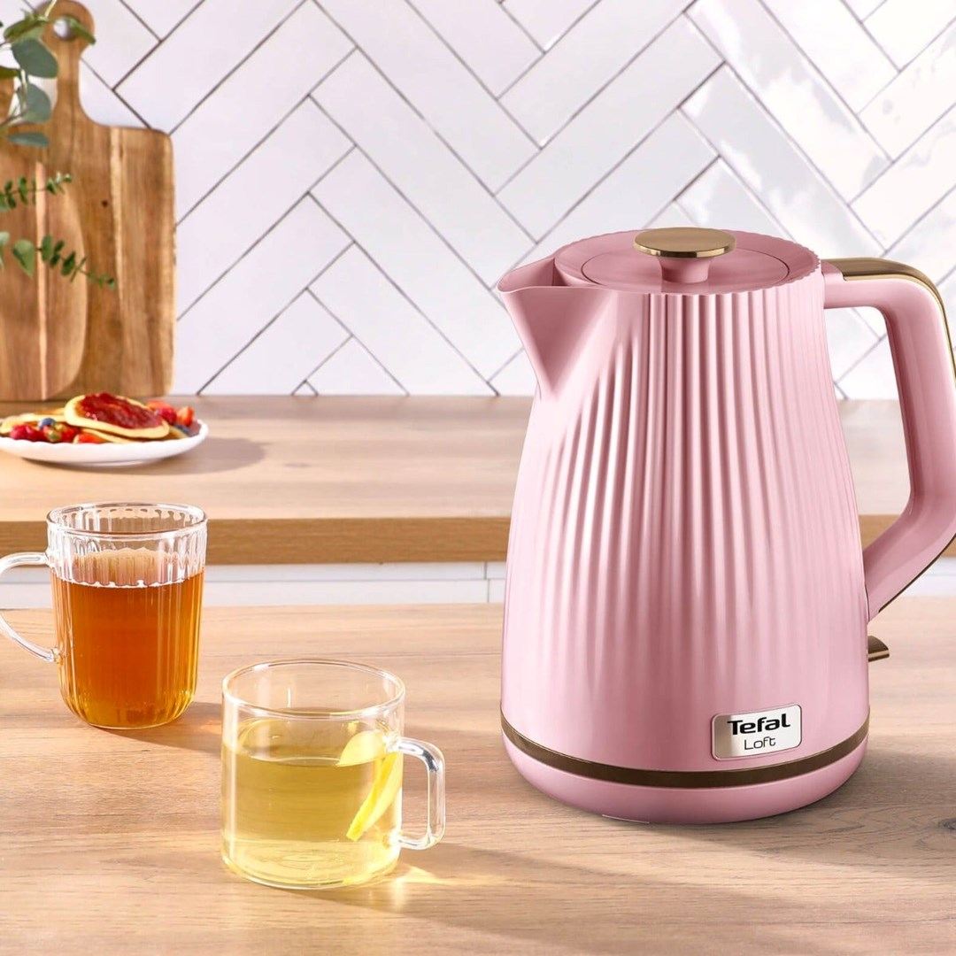 Różowy czajnik Tefal Loft i dwie szklanki z herbatą stoją na drewnianym blacie kuchennym.
