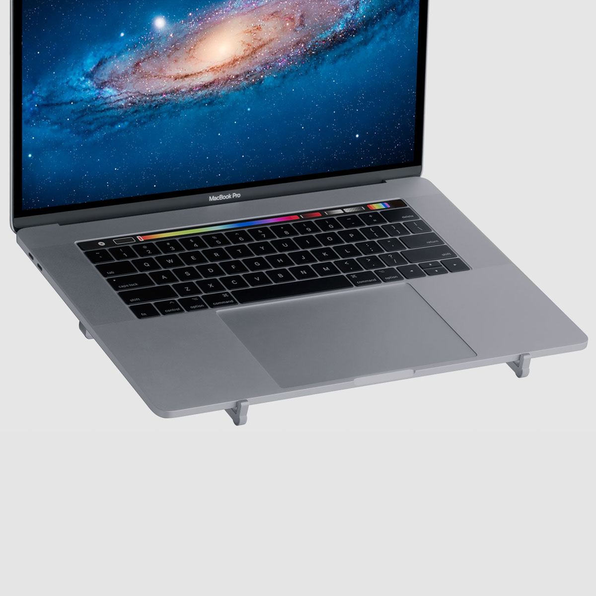 Ein silberner Laptop mit Touch Bar steht auf einem grauen Ständer vor einem neutralen Hintergrund.