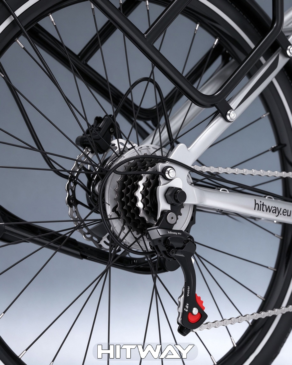 Nahaufnahme des silbernen Fahrrad-Hinterrads mit Kette, Gangschaltung, Scheibenbremse und Gepäckträger.