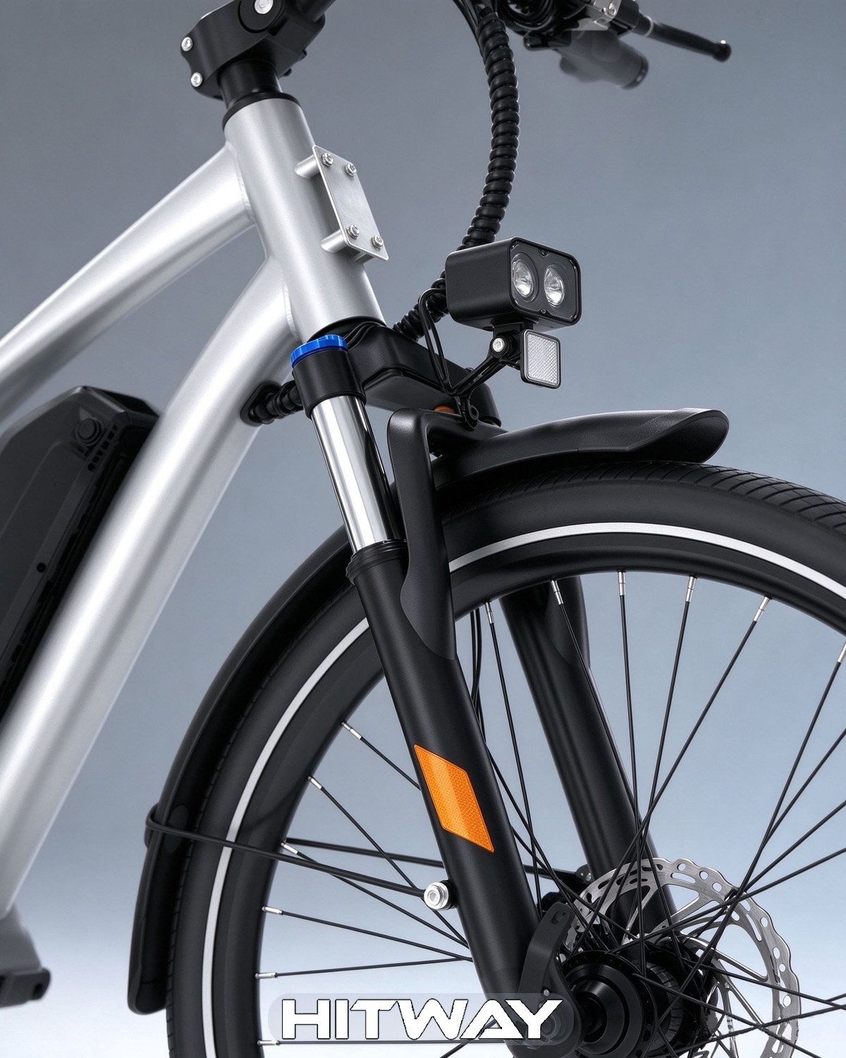 Nahaufnahme der Frontgabel und des Vorderraums eines silbernen E-Bikes vor grauem Hintergrund.