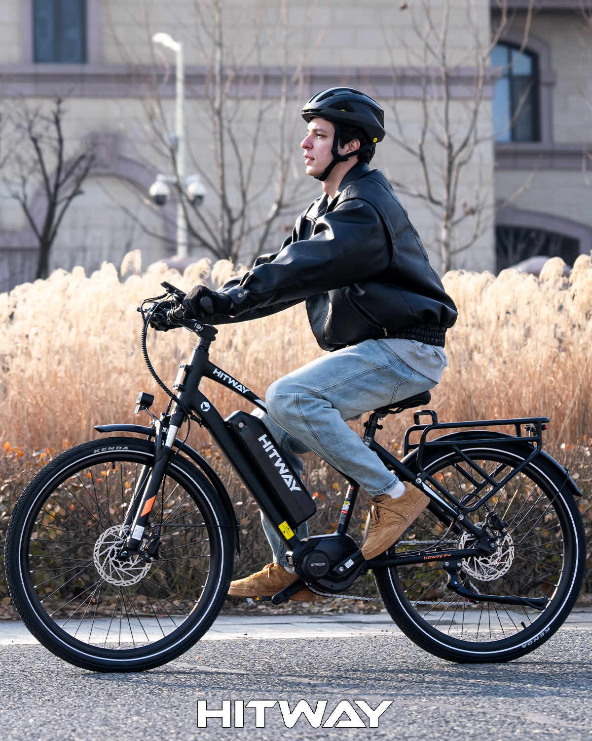 Ein Mann mit Helm und Lederjacke fährt ein schwarzes Hitway-E-Bike auf einer städtischen Straße.