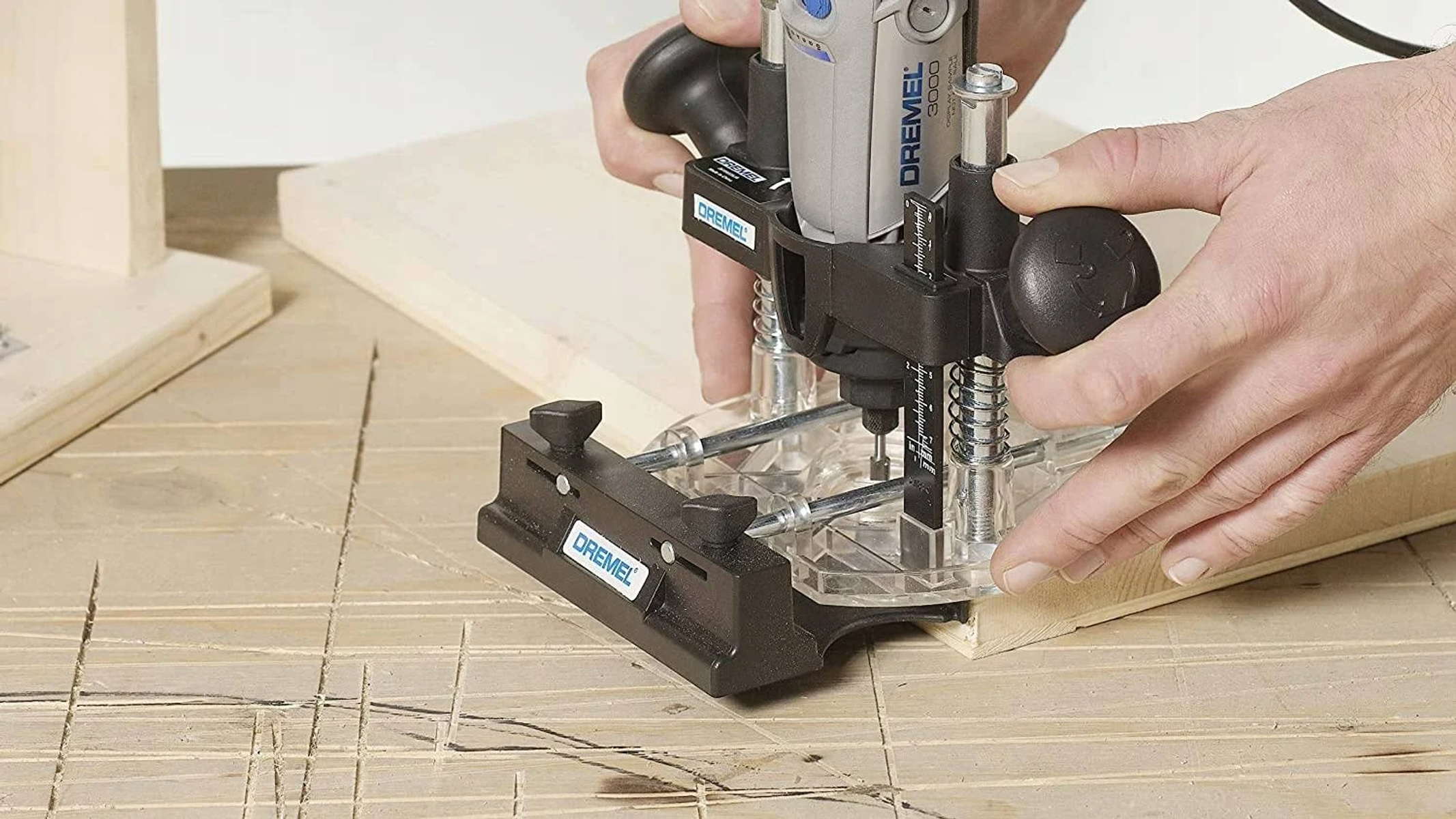 Person führt eine Dremel-Fräse auf einem Holzbrett.
