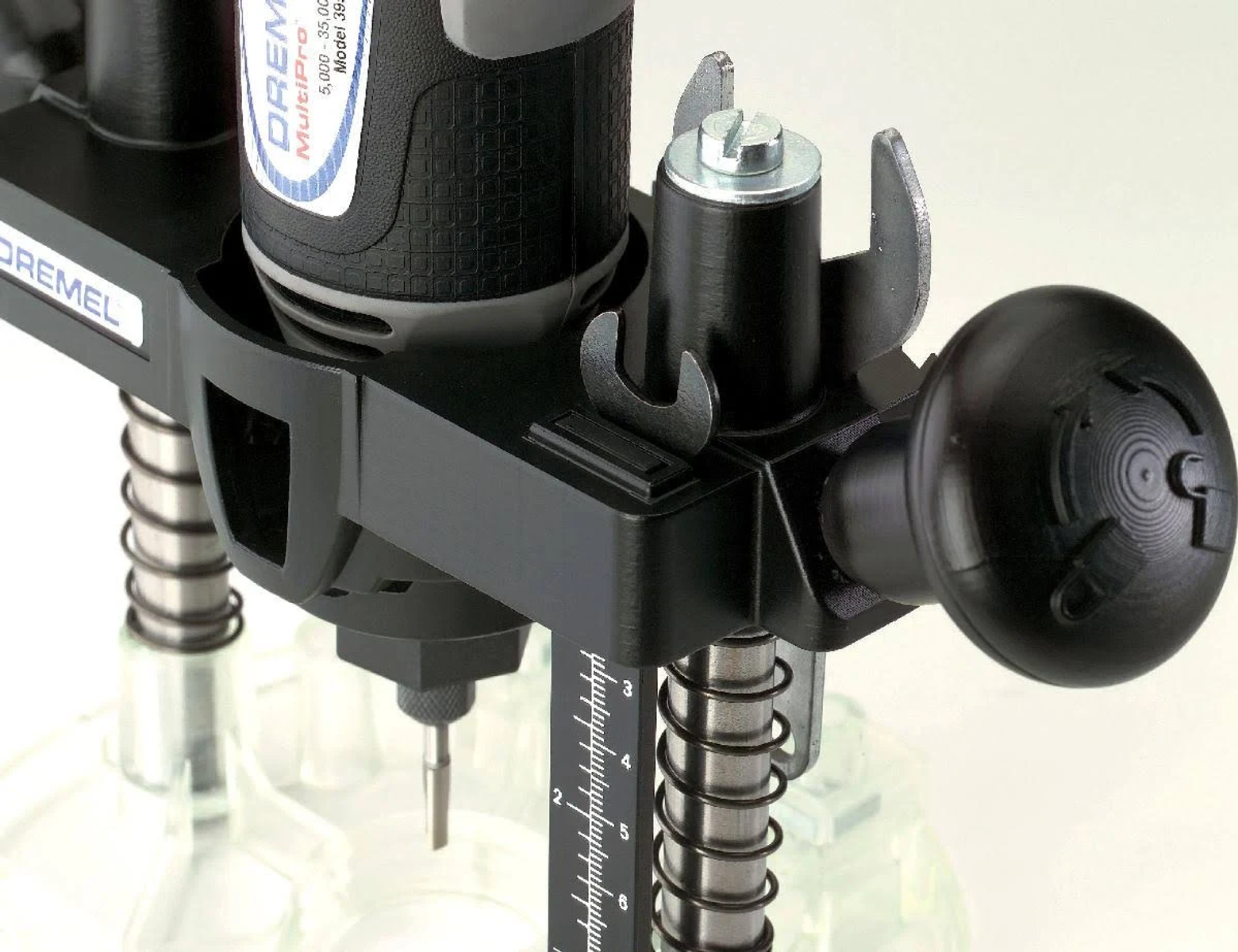 Nahaufnahme einer schwarzen Dremel-Frässtation mit Tiefenskala, Schrauben und Knöpfen vor hellem Hintergrund.