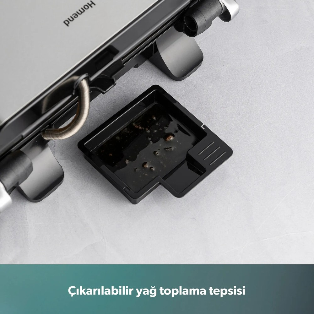 Gri bir yüzey üzerinde çıkarılabilir siyah yağ toplama tepsisine sahip gri bir ızgara makinesi.