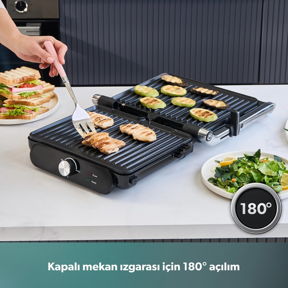 Beyaz tezgah üzerinde tavuk, sebze, sandviç ve salata olan açık elektrikli ızgara.