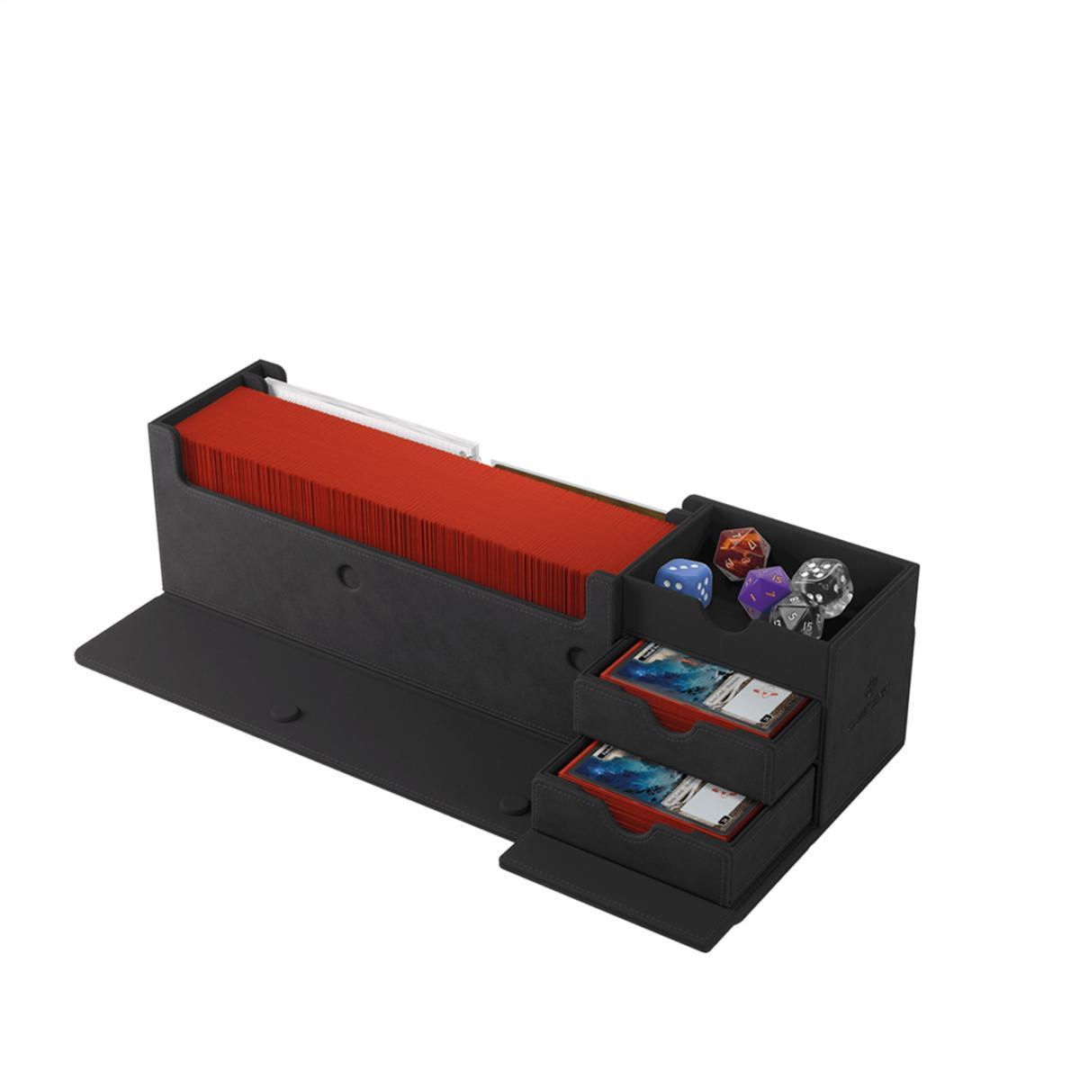 Caja negra de almacenamiento con cartas rojas, dados coloridos y dos cajones pequeños con mazos sobre fondo blanco.