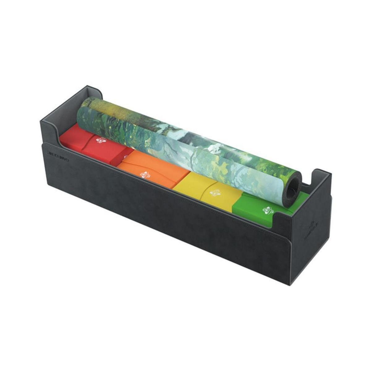Una caja de almacenamiento negra que contiene cajas de mazos coloridas y un tapete enrollado encima.
