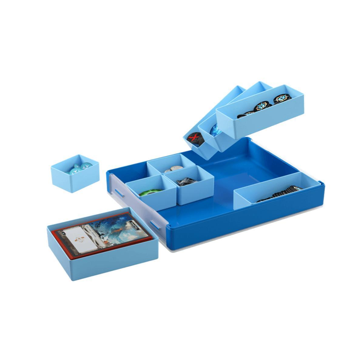 Cajas organizadoras de juegos de mesa azules con cartas, fichas y compartimentos en fondo blanco.