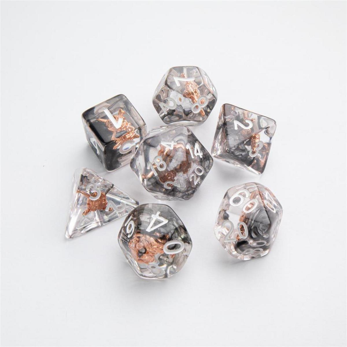 Un juego de siete dados transparentes con números blancos y pequeñas figuras de dragón de bronce en su interior, sobre fondo blanco.