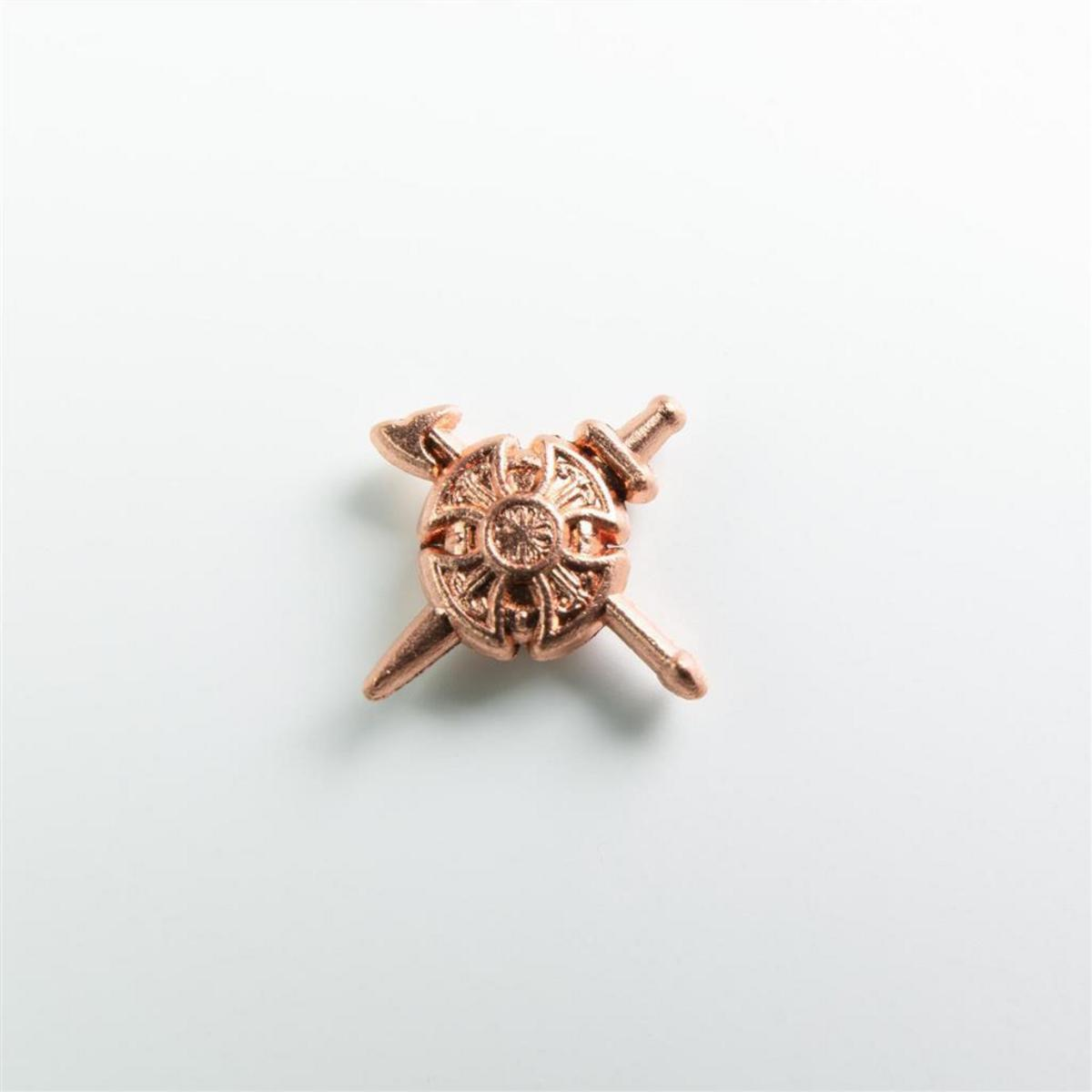 Una insignia de metal de color cobre muestra un escudo redondo con dos armas cruzadas sobre fondo blanco.