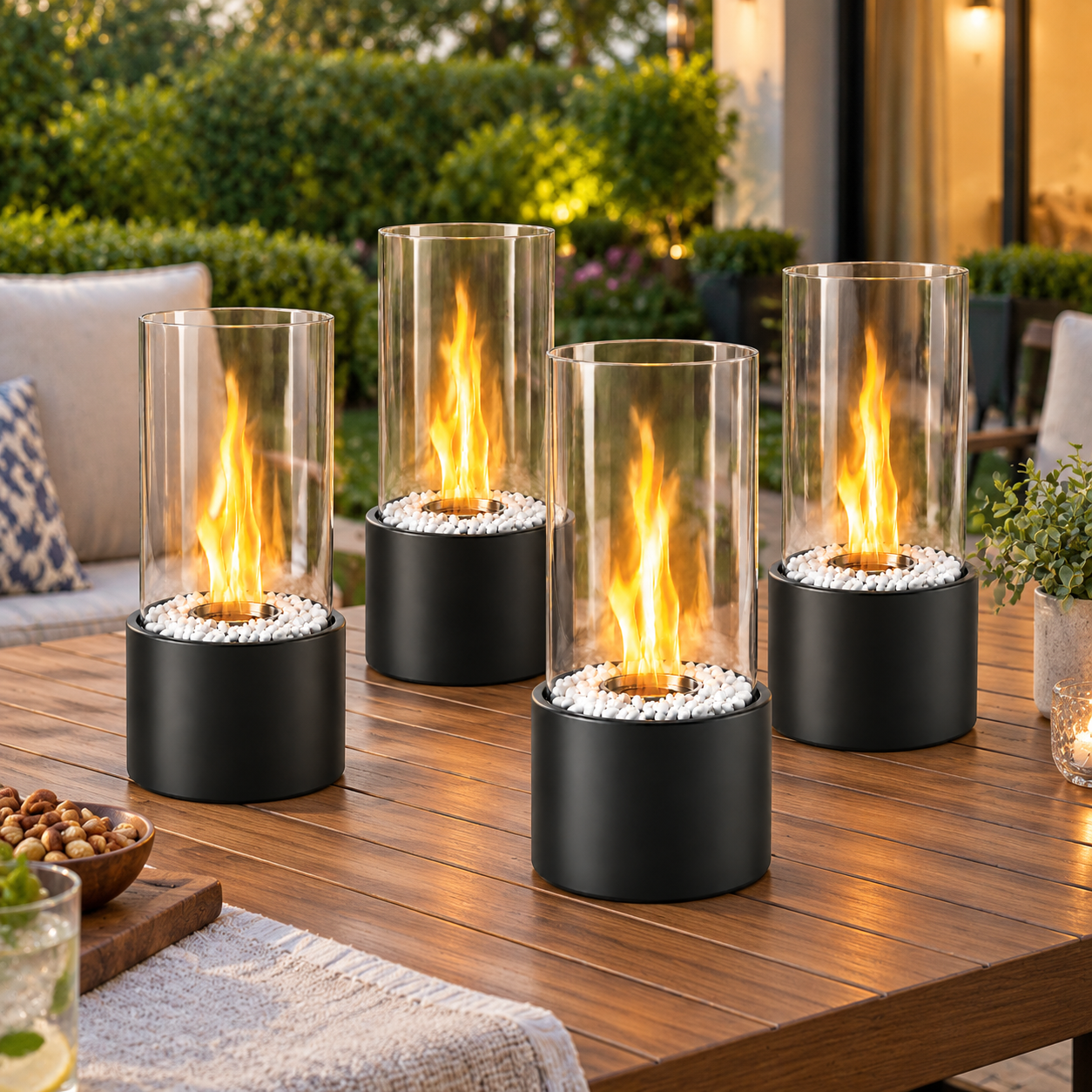 Vier moderne schwarze Tischkamine mit Glaszylinder und Flammen stehen auf einem Holztisch im Garten.