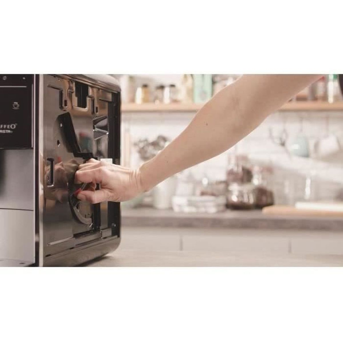Una mano apre o chiude lo sportello di una macchina da caffè in cucina.