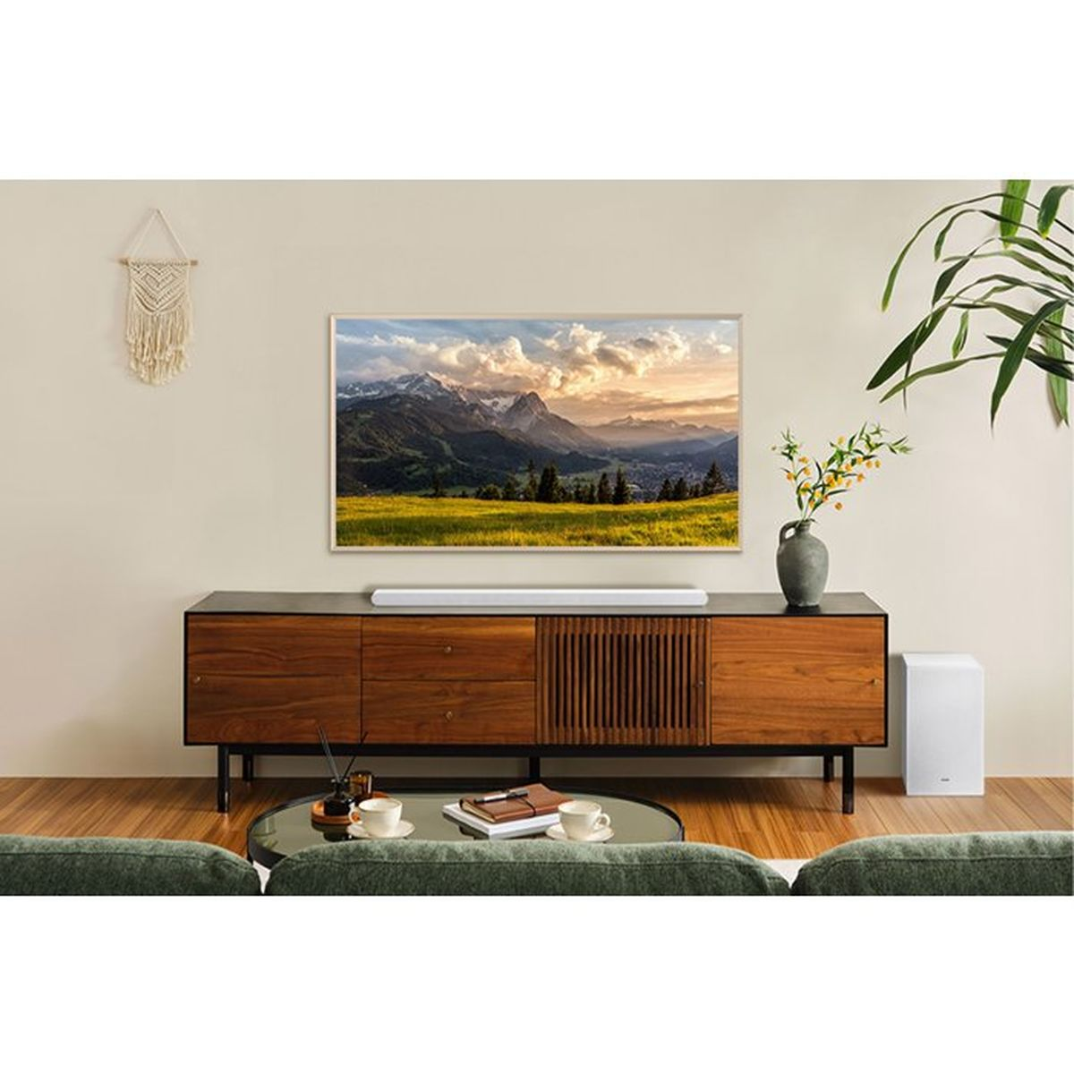 Soggiorno con credenza in legno, TV con paesaggio montano e tavolino.