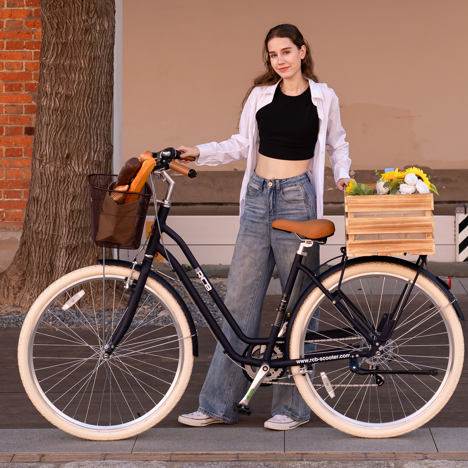 Eine Frau steht im Freien neben einem Fahrrad mit Brotkorb und Holzkiste voller Blumen.