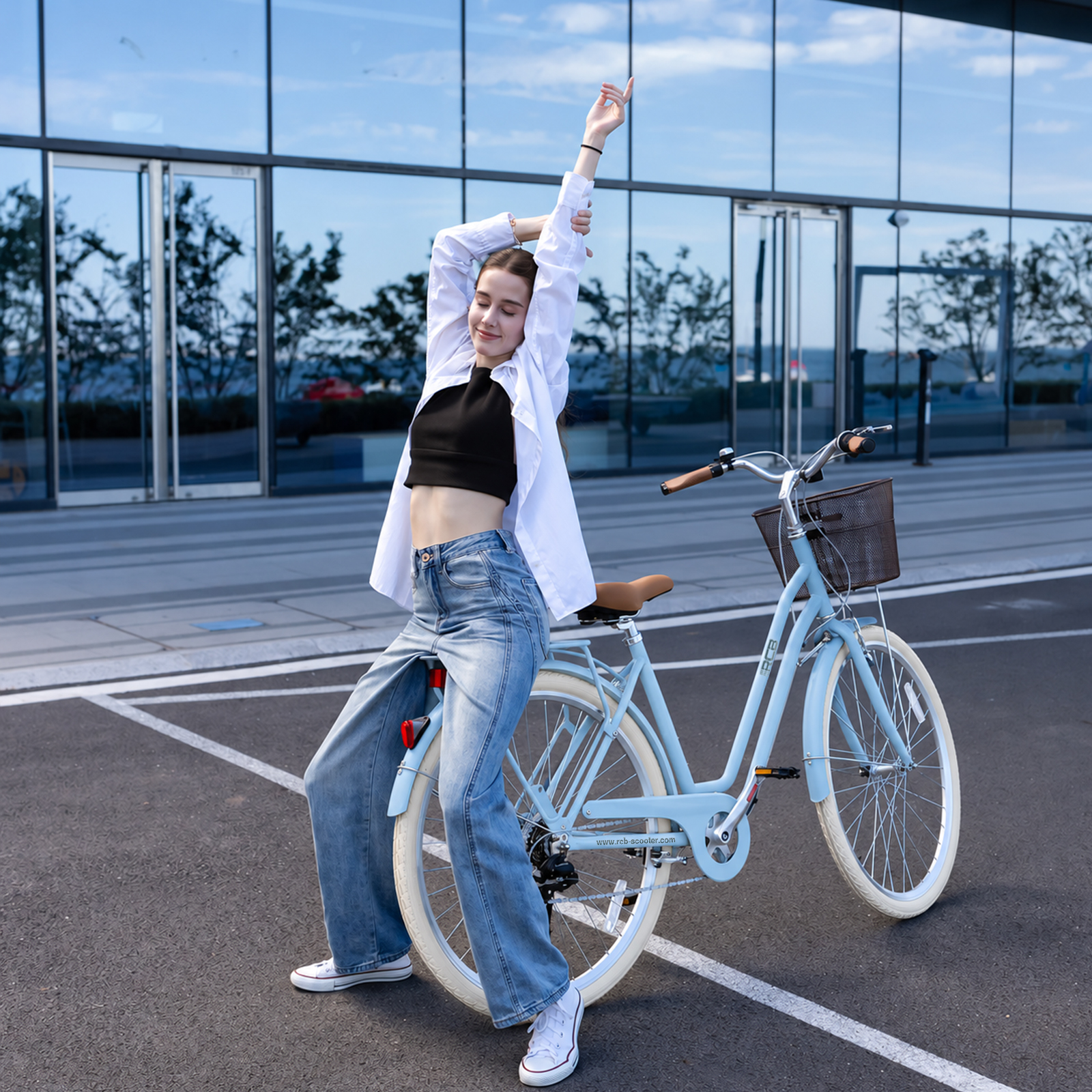 Eine Frau in Jeans und weißem Hemd streckt sich auf einem hellblauen Fahrrad vor einer Glasfassade.