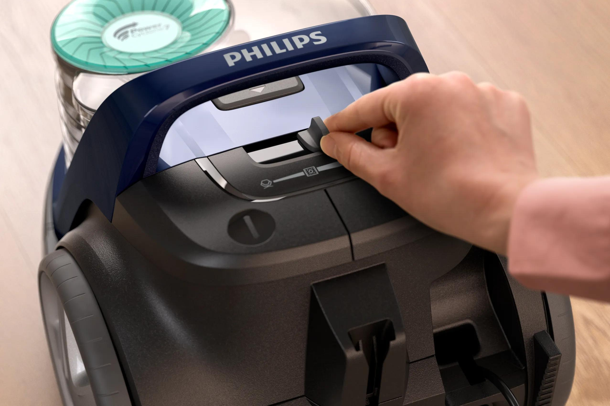 Una mano regola il controllo a scorrimento su un aspirapolvere Philips blu e nero.