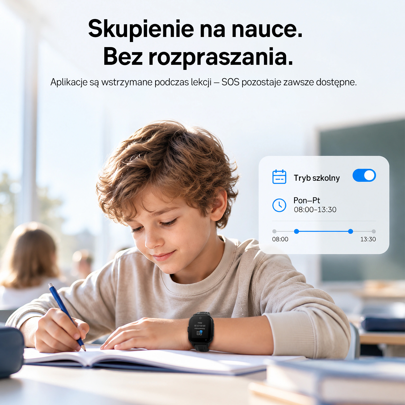 Chłopiec pisze w zeszycie w klasie, mając na ręku smartwatch w trybie szkolnym.