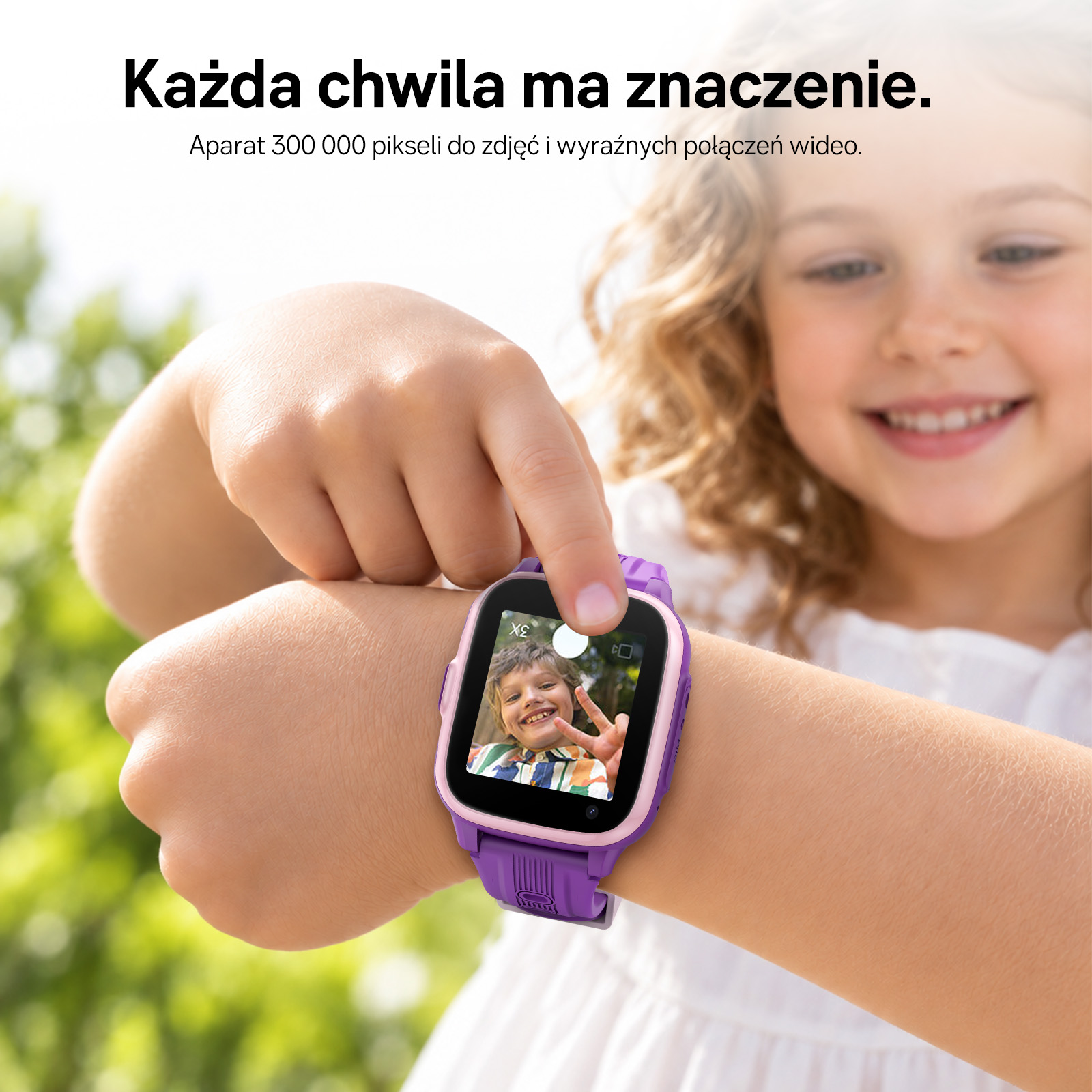 Uśmiechnięta dziewczynka dotyka ekranu fioletowego smartwatcha na nadgarstku ze zdjęciem.