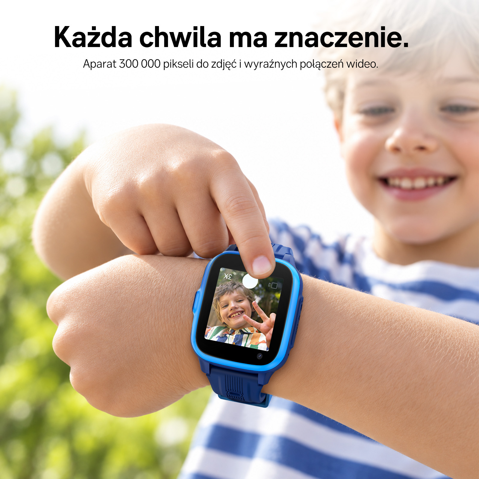 Chłopiec dumnie pokazuje niebieski smartwatch na nadgarstku ze zdjęciem na ekranie.