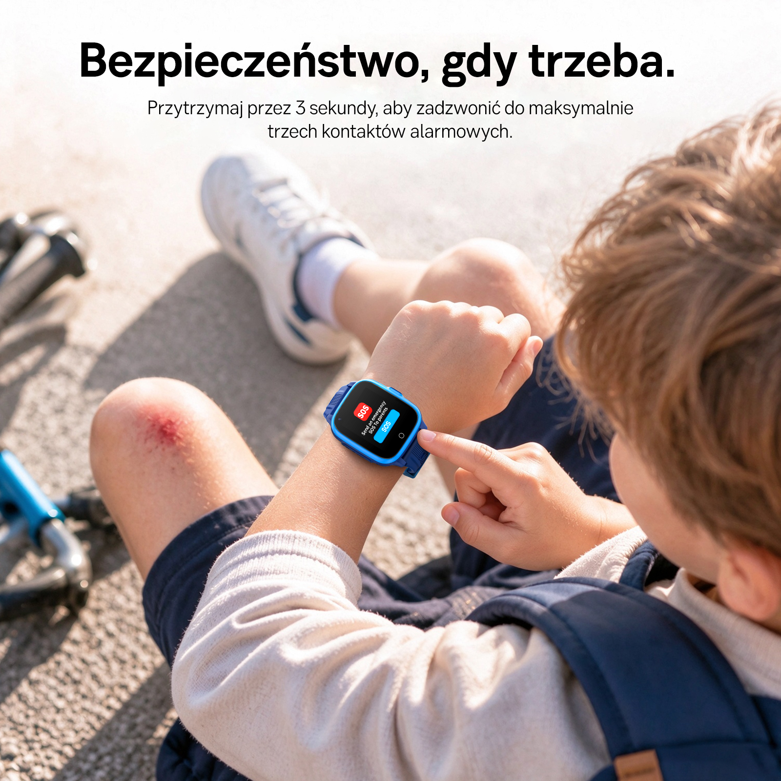 Dziecko siedzi na zewnątrz i naciska przycisk SOS na niebieskim smartwatchu, z obtarciem na kolanie.